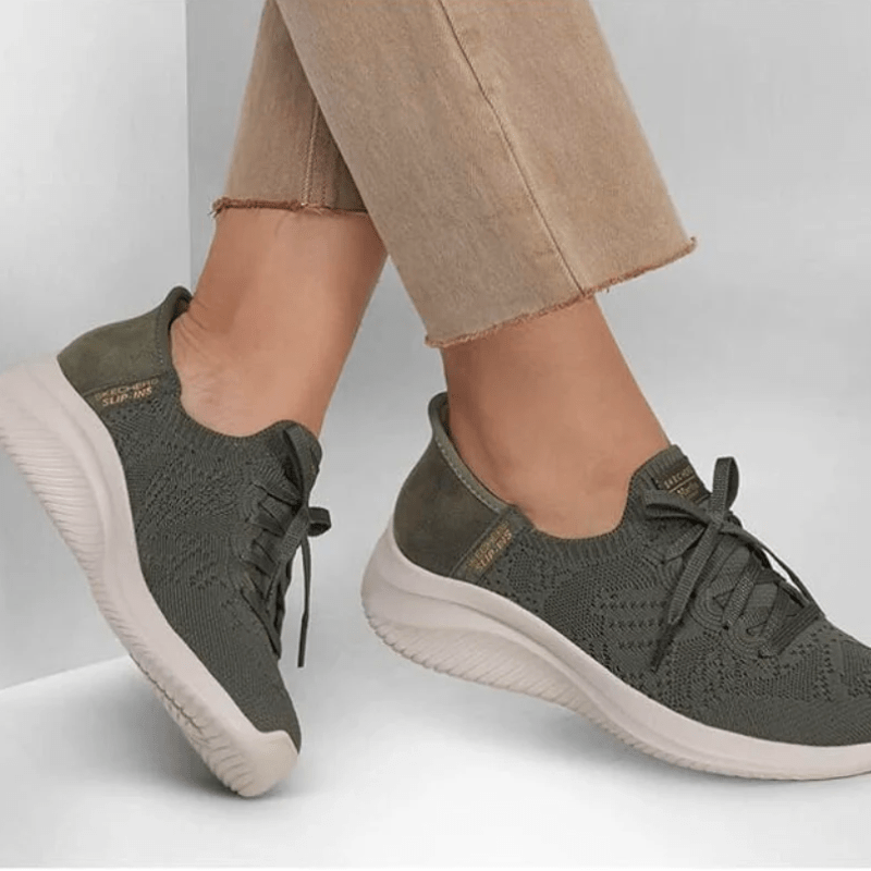 Ett par olivgröna Skechers slip-in damsneakers på fötter med beige byxor, visar hur de sitter