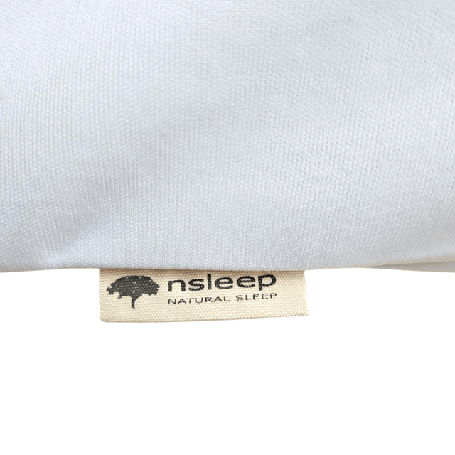 Närbild på en beige tygetikett med texten "nsleep NATURAL SLEEP" och en trädlogga på ett vitt örngott