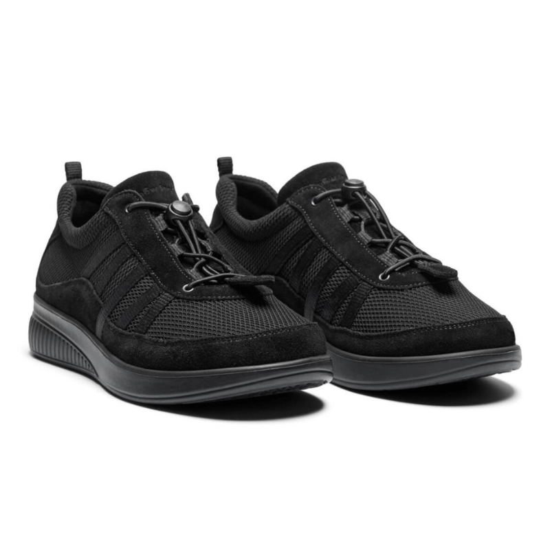 Ett par svarta New Feet damsneakers med mesh och elastisk snörning, sedda snett framifrån