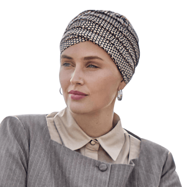 Kvinna bär en beige Yoga turban med svart ormskinnsmönster, matchande en grå jacka och beige skjorta