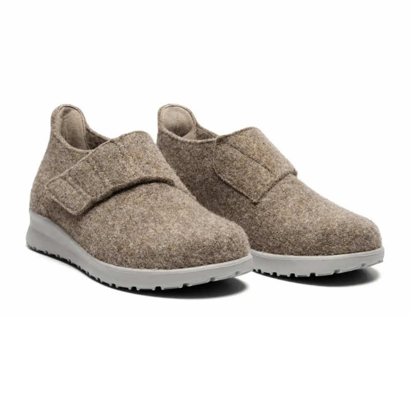 Ett par sandfärgade New Feet damtofflor i ull med kardborreband, sedda snett framifrån