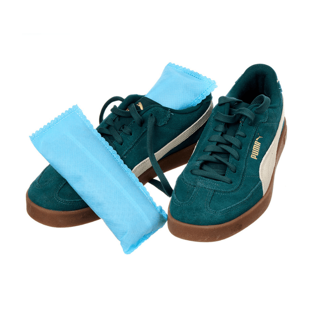Två gröna sneakers med blå Shoe Buddy luktborttagare insatta i varje sko, redo att absorbera lukt