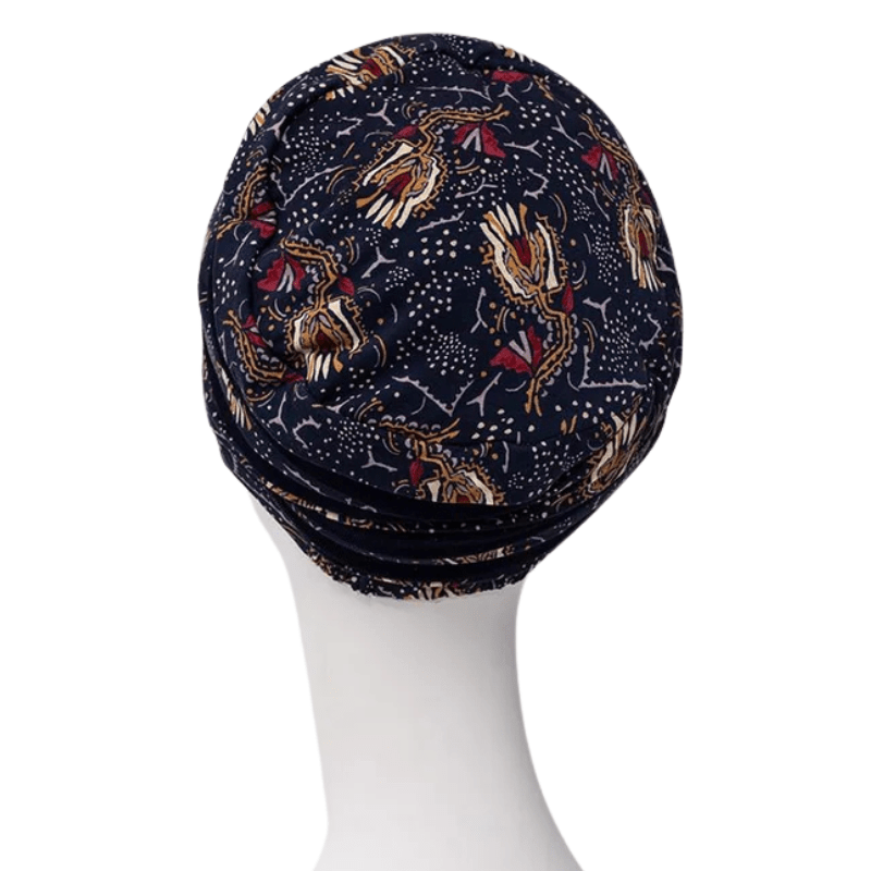 Shanti turban i Amber Garden-mönster med samlat tyg baktill, visad på en vit skyltdocka sedd bakifrån