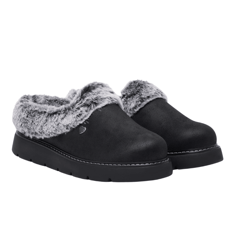 Et par sorte Skechers damehjemmesko med grå kunstpels og ruskind-look, set let skråt forfra