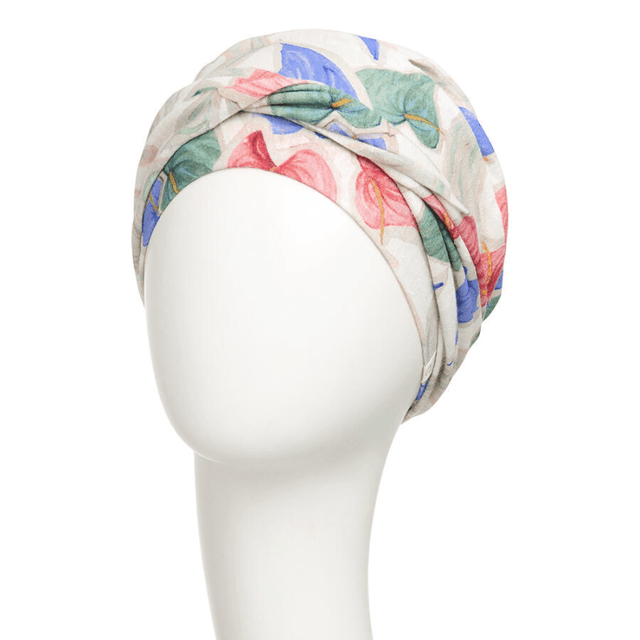 Shakti turban i tropiskt blommönster sedd framifrån på skyltdocka, med elegant knutdetalj