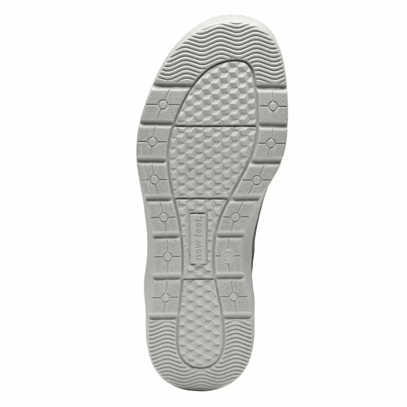 Undersidan av en New Feet herrsko med ljus sula och mönster, samt New Feet-logotypen