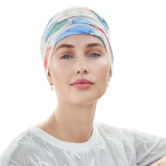 Kvinna bär en vit Yoga turban "Tropical blossom" med färgglada blommor och blad, sedd framifrån