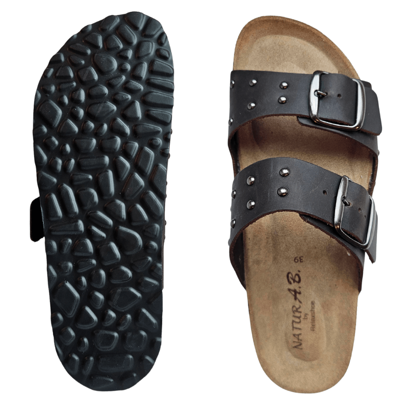 Relaxshoe damtoffel i mörkbrunt skinn med spännen och nitdetaljer, samt en bild på den svarta mönstrade sulan