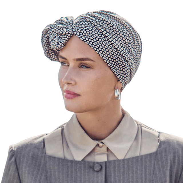 Kvinna bär en beige Shakti turban med ormskinnsmönster, stylad med volym framtill