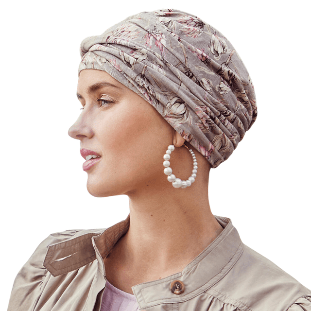 Kvinna i profil bär en mönstrad Shakti turban med Protea love-mönster och pärlörhängen