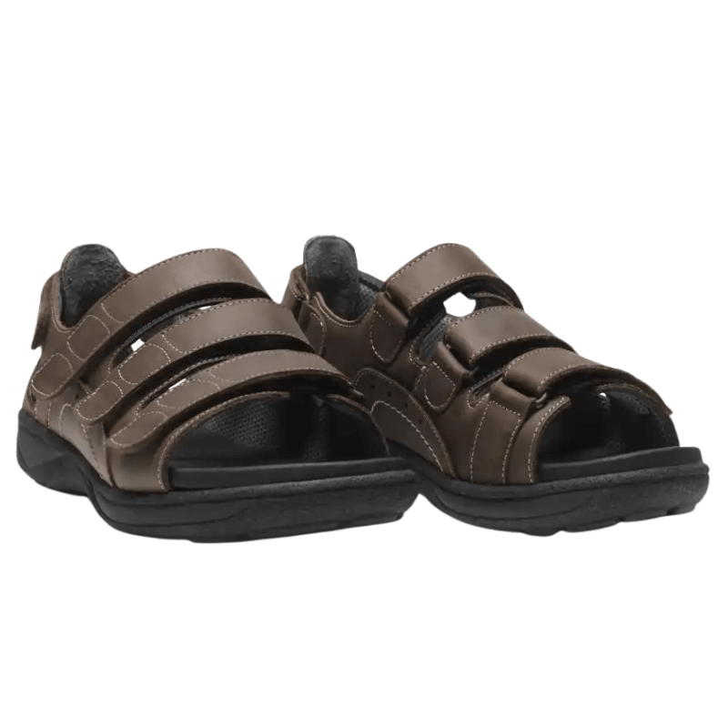 Ett par bruna New Feet herrsandaler med kardborreband, sedda snett framifrån på vit bakgrund