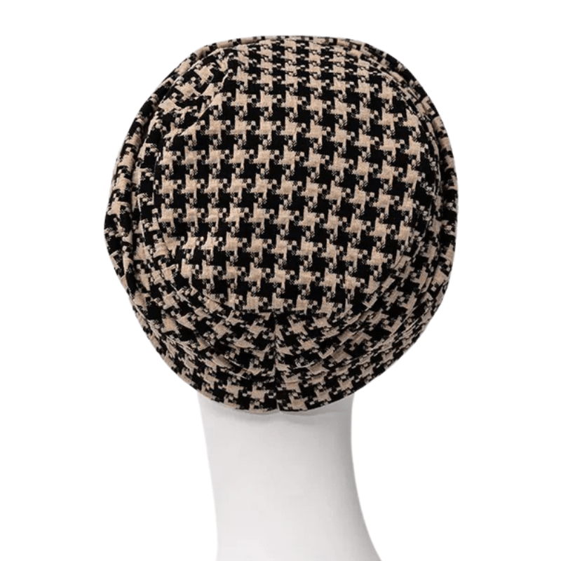 Lea turban i svart och beige hundtandsmönster på skyltdocka, sedd bakifrån med mjuk volym i nacken