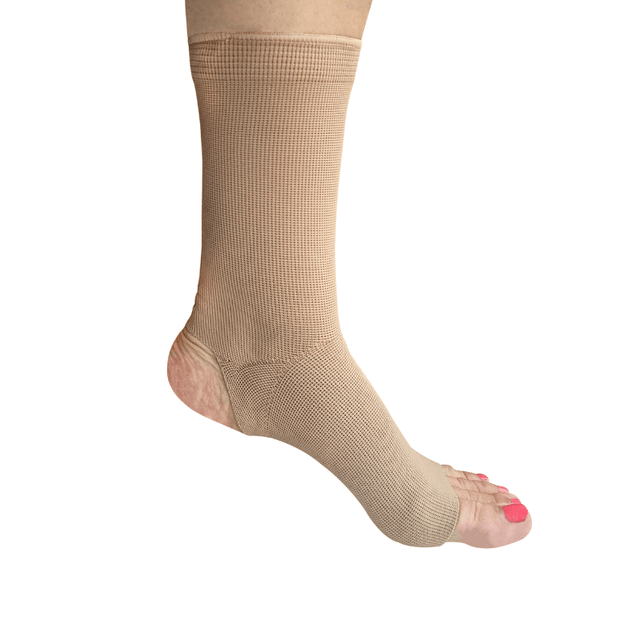 Beige elastisk ankelstrumpa med öppen häl och tå, sedd på en fot från sidan
