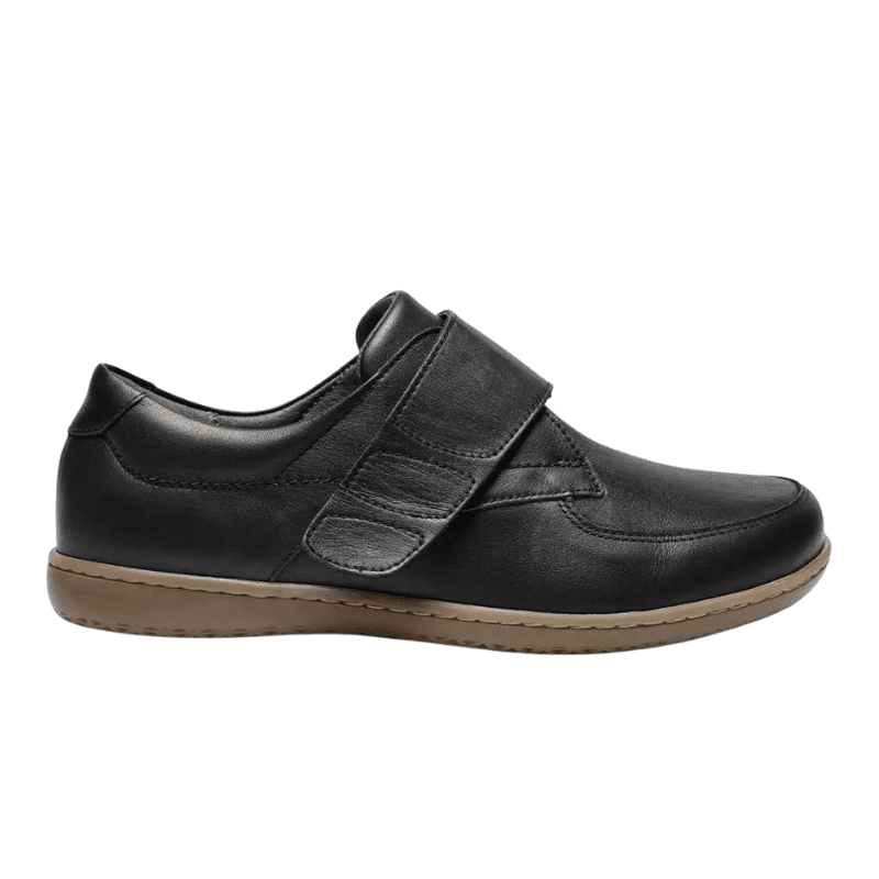 Svart New Feet damsko i läder med bred kardborrerem, sedd från sidan med beige sula