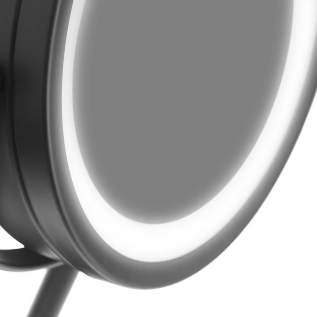 Tæt på sort makeup-spejls kant med tændt LED-lys, der fremhæver den oplyste ring
