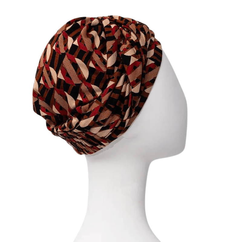 Sapphire Boho turban i Tribal Art-design med varma färger, sedd från vänster sida på en vit skyltdocka
