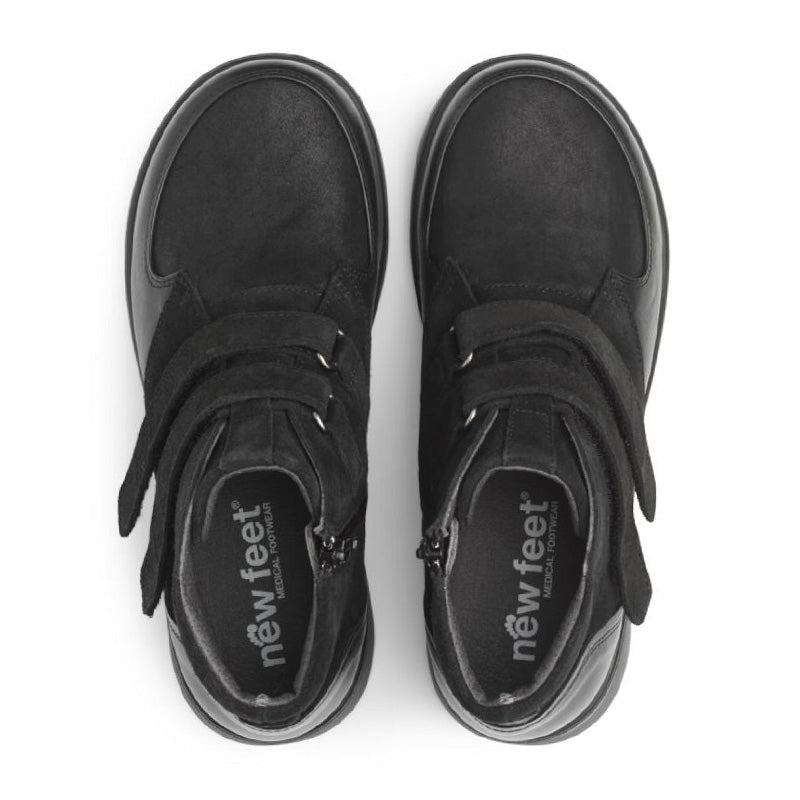 Ovanifrån bild av två svarta New Feet damkängor, med logotyp på den urtagbara innersulan