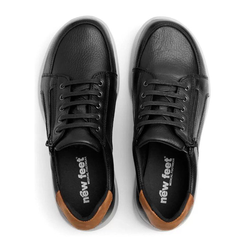 Ovanifrån vy av två svarta New Feet herrskor med märkets logotyp på innersulorna