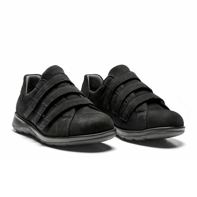 Ett par svarta New Feet damskor i nubuck med kardborreband, sedda snett framifrån