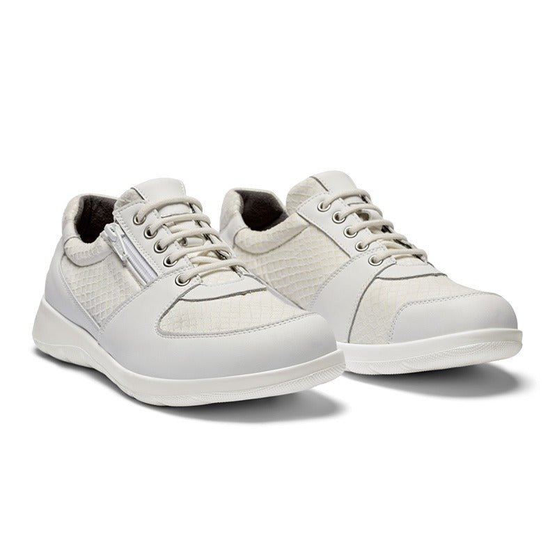 Ett par vita New Feet damsneakers i läder med snörning och dragkedja, sedda snett framifrån