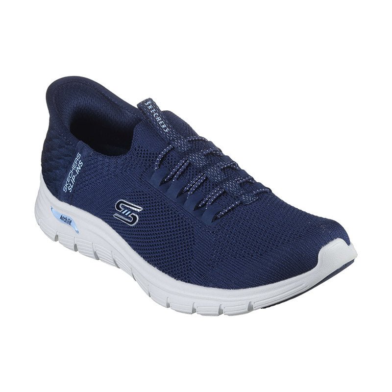 Från sned vinkel syns den marinblå Skechers damsneakern med elastiska snören och vit sula