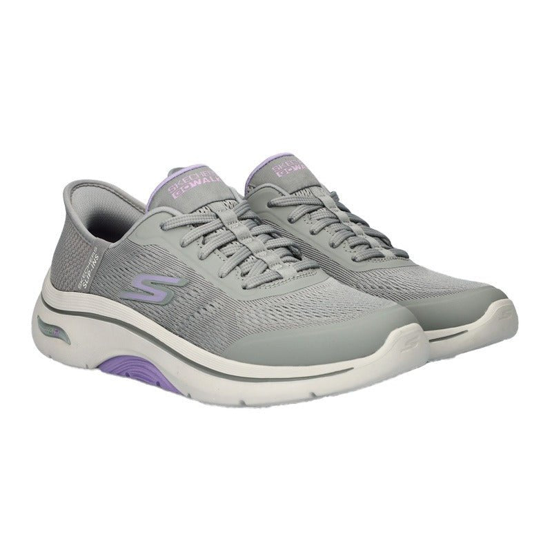 Ett par grå Skechers slip-in damsneakers i stickat textilmaterial, med vit sula och lila detaljer, sedda snett framifrån