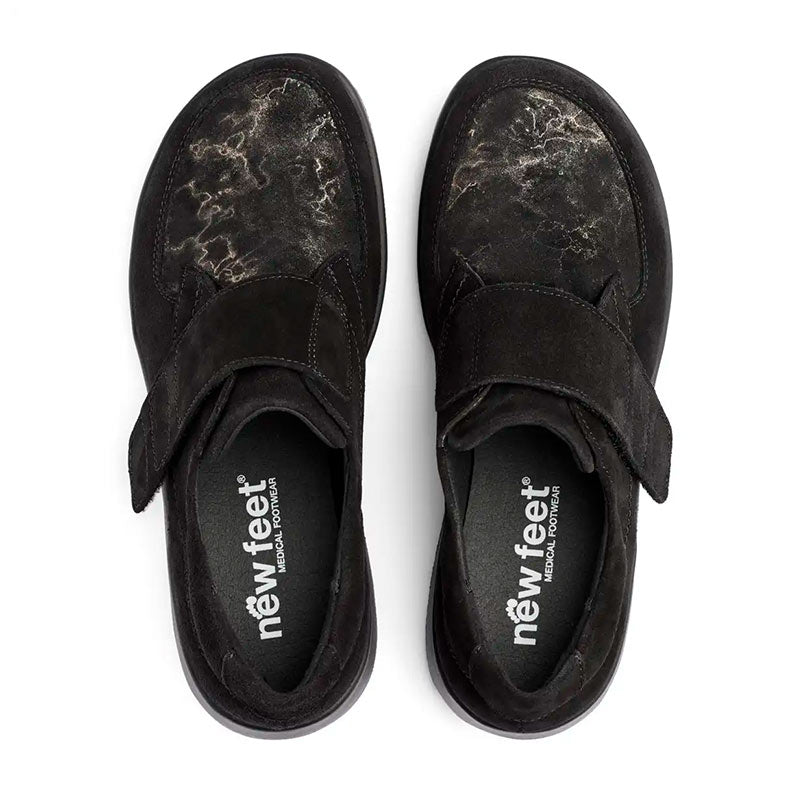 New Feet damskor i svart mocka, sedda uppifrån. Innersulorna med New Feet logotyp och mönstrad ovansida syns