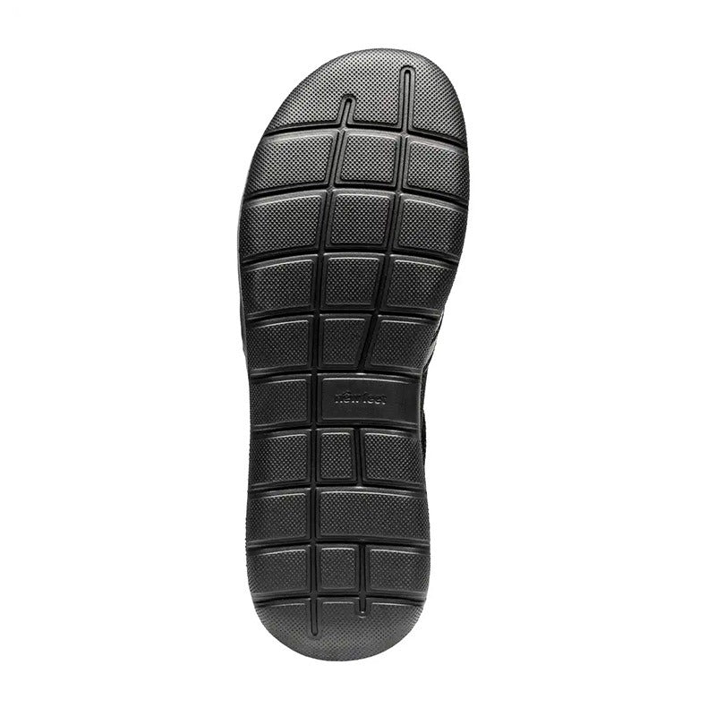 Svart halksäker yttersula från en New Feet damsko, sedd underifrån. Sulan har ett tydligt rutmönster