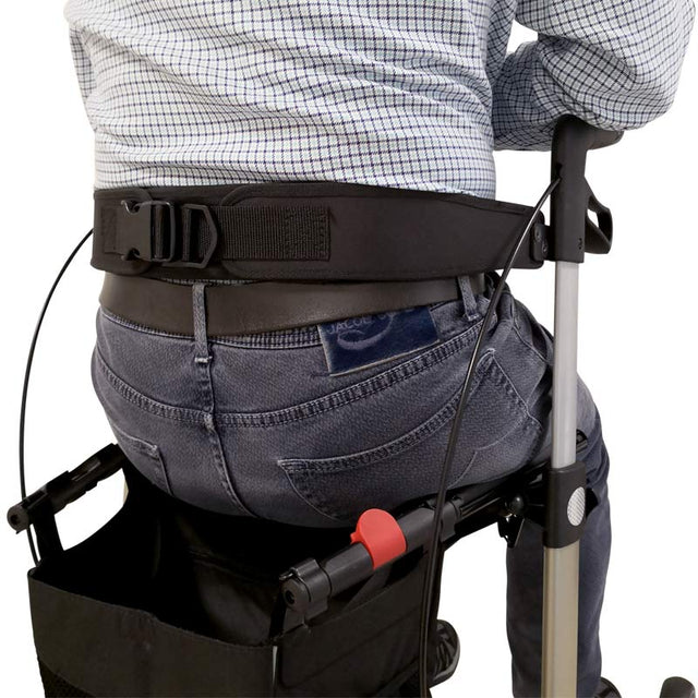 Ryggstöd till rollator i bruk, sett bakifrån på en person som sitter på rollatorn med ryggstödet runt ländryggen