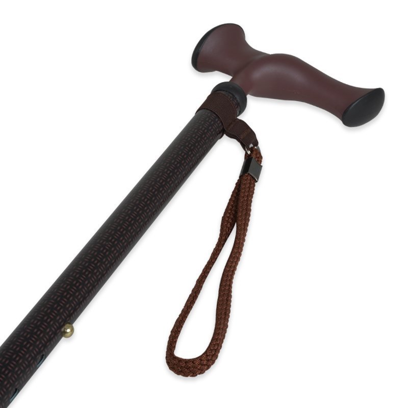 Käpp med brunt anatomiskt grepp, mörkbrun mönstrad stav och en kopparfärgad handledsrem, sedd snett uppifrån