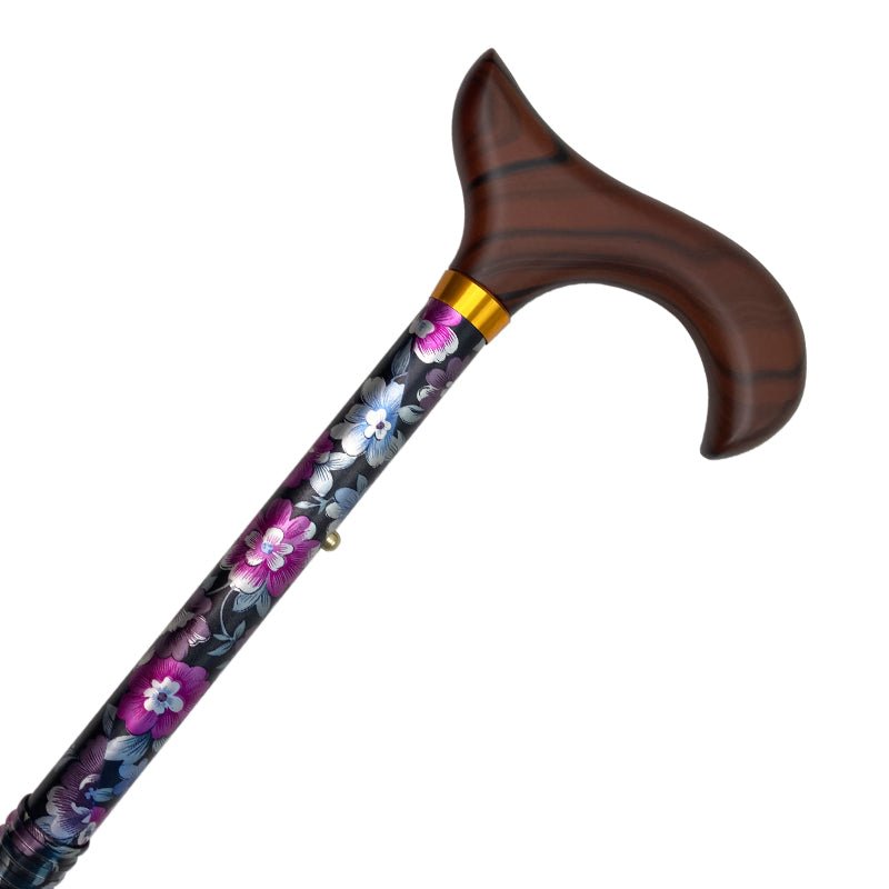 Närbild på en hopfällbar käpp med mörkt trähandtag och svart skaft med blå, grå och lila blommor