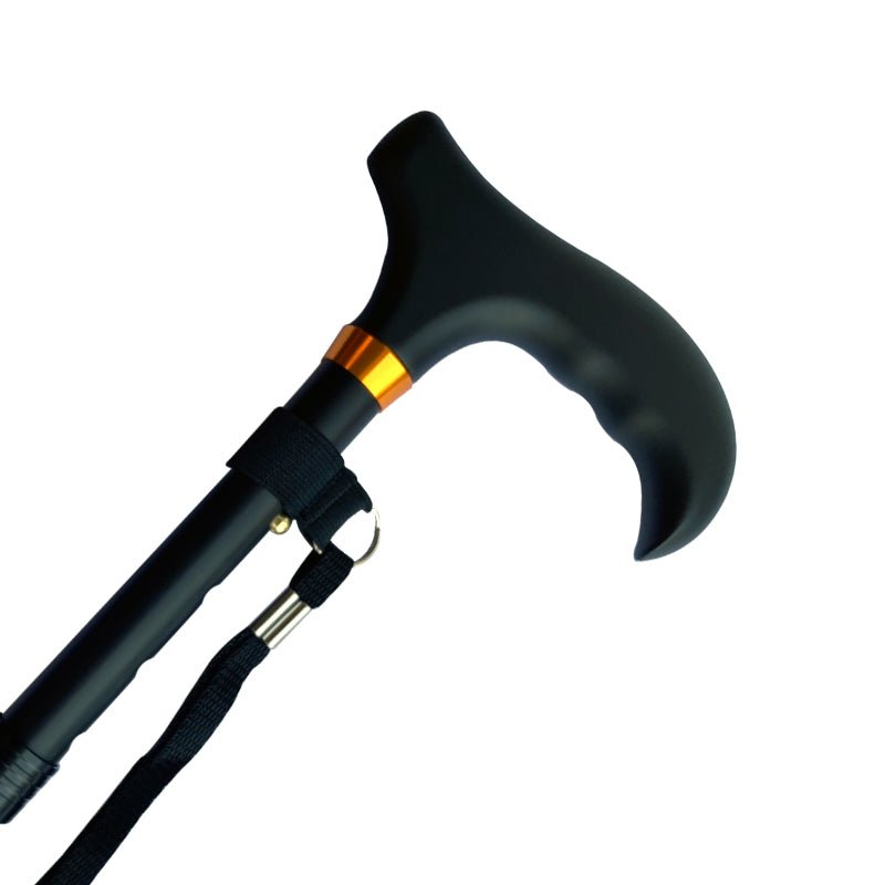 Närbild på svart hopfällbar käpp med ergonomiskt handtag, bronsfärgad ring och handledsrem