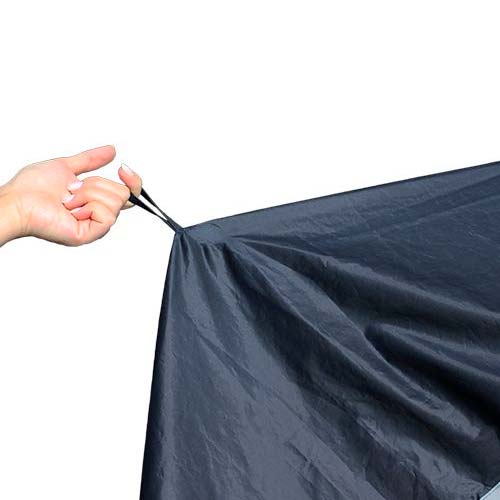Närbild på en hand som håller i ett elastiskt band på det mörkblå regnskyddet för rullator