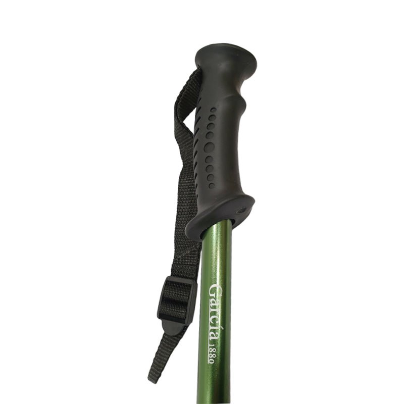 Närbild på den gröna vandringsstavens svarta ergonomiska handtag med handledsrem och logotyp