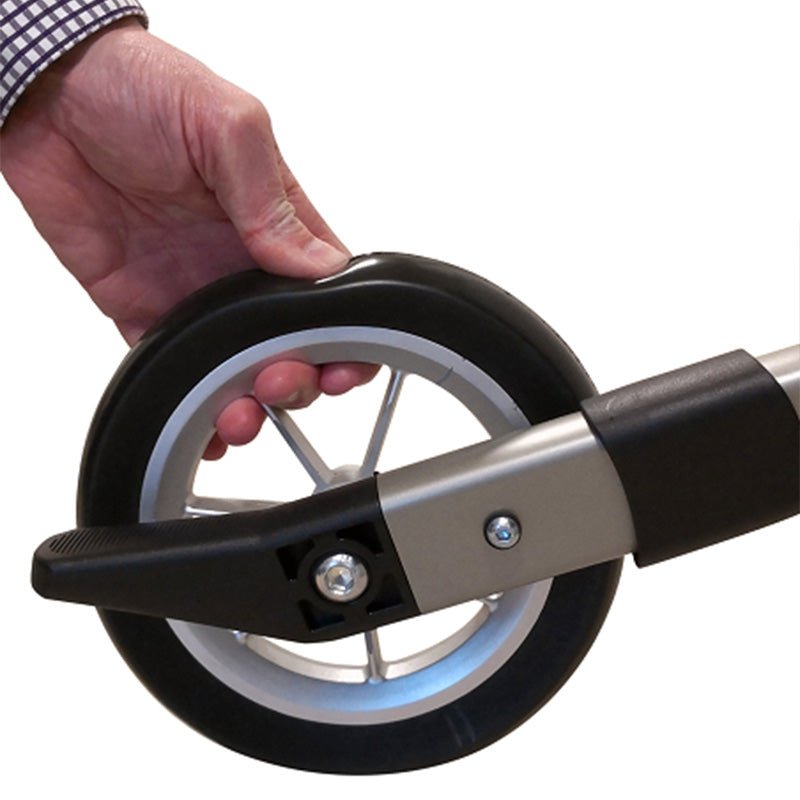 En hand trycker på ett mjukt, vibrationsdämpande rollatorhjul med silverfärgade ekrar och svart däck