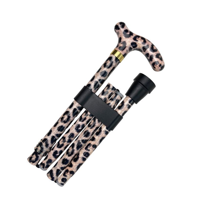 Hopfällbar käpp med leopardmönster, hopfälld och säkrad med ett svart band, redo att packas ner