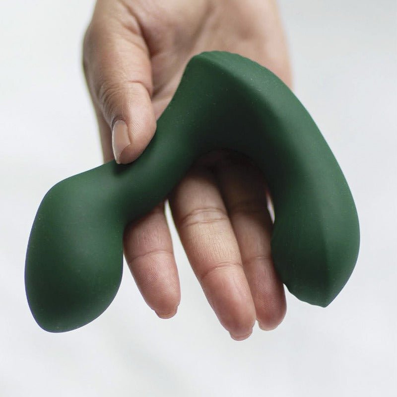 En hand håller den mörkgröna Birch prostatavibratorn och visar dess flexibla, böjda form