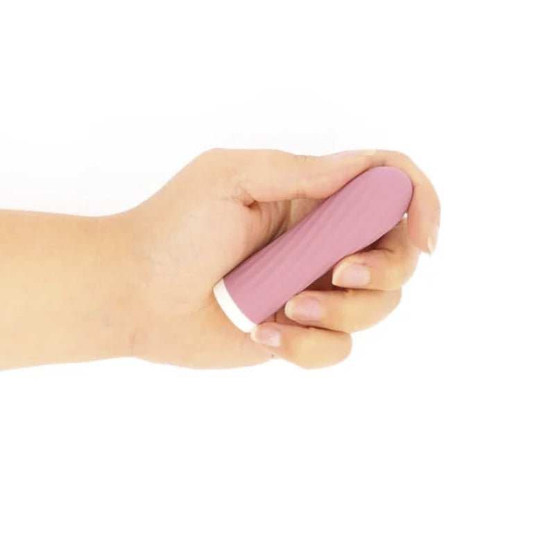 En hand håller den kompakta rosa Bullie vibratorn med räfflad yta och vit bas