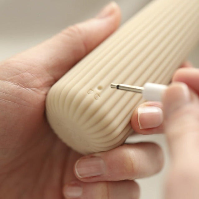 Närbild på en hand som ansluter laddkabeln till den uppladdningsbara Corny vibratorns bas