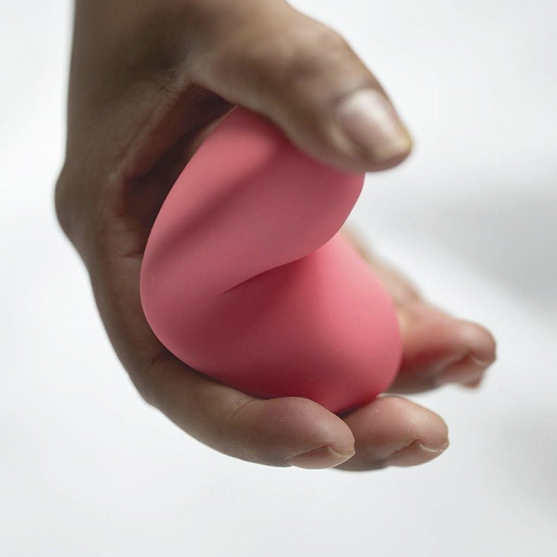 En hand som klämmer den rosa vibratorn, vilket visar dess flexibla och mjuka silikonmaterial