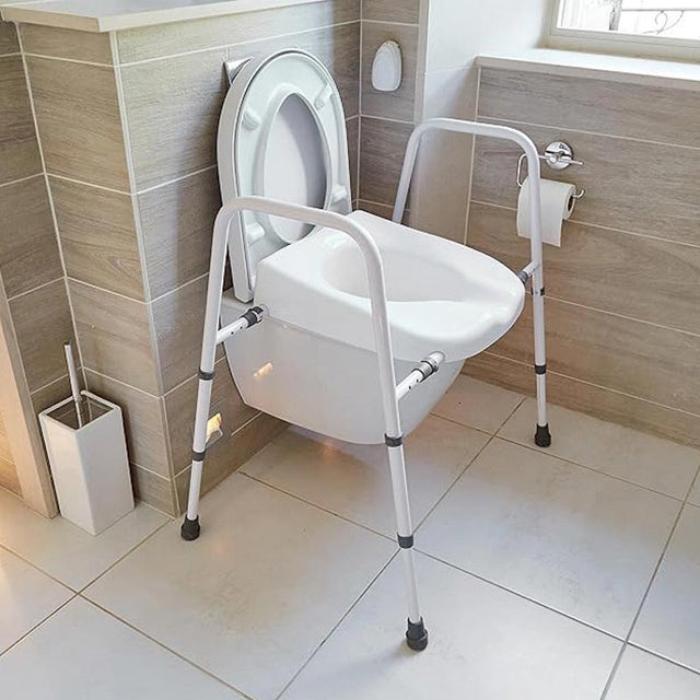 Justerbar toiletstol placeret over et hvidt toilet i et moderne badeværelse, set skråt forfra