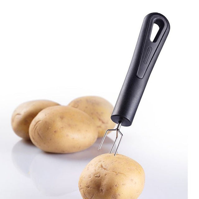 Svart potatishållare med metallpiggar som håller en ljusbrun potatis, med fler potatisar i bakgrunden