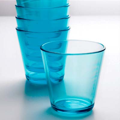 En stapel med flera blåa plastglas i konisk form, med ett glas framför på en ljus yta