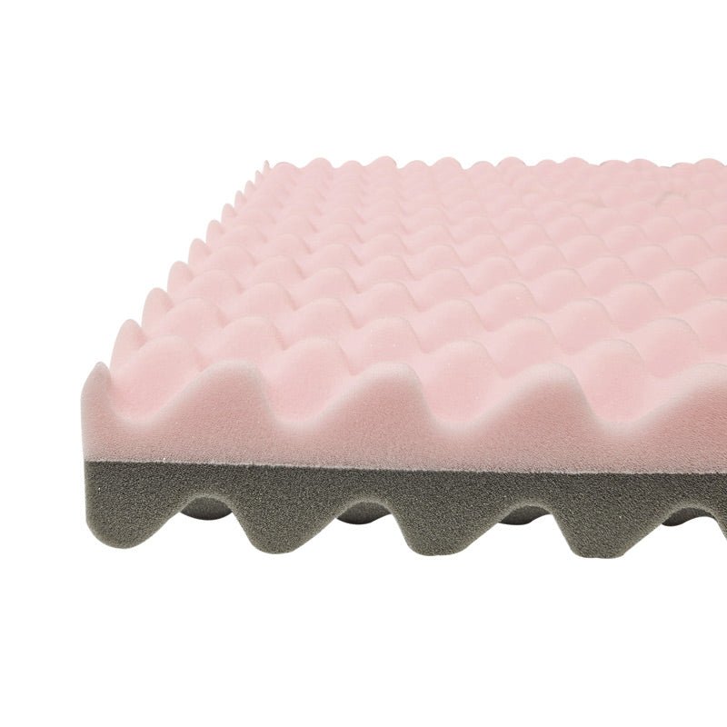 Närbild på den rosa tryckavlastande sittdynans vågiga yta och grå bottenlager från sidan