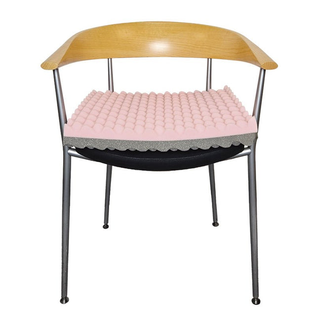 En tryckavlastande sittdyna i rosa och grått placerad på en modern stol med trärygg