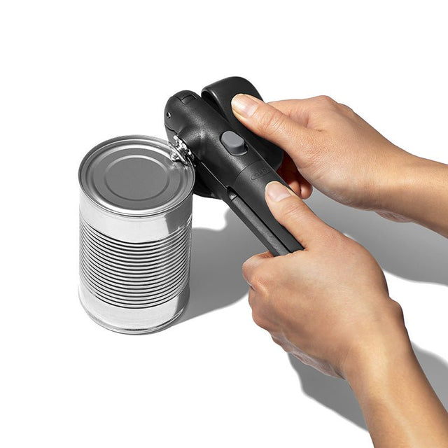 Händer som använder den svarta OXO Lock & Go konservöppnaren för att enkelt öppna en silverfärgad konservburk