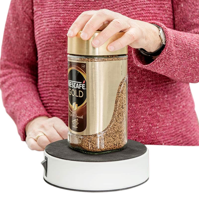 En person öppnar en kaffeburk med en hand med hjälp av en vit och svart Easy-Up® burköppnare