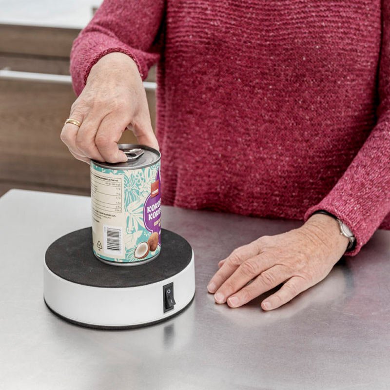 En hand använder Easy-Up® hållaren för att öppna en konservburk på en metallbänk