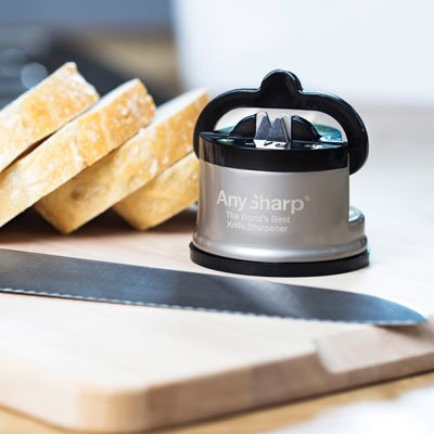 AnySharp PRO knivslip på en träskärbräda bredvid skivat bröd och en tandad brödkniv