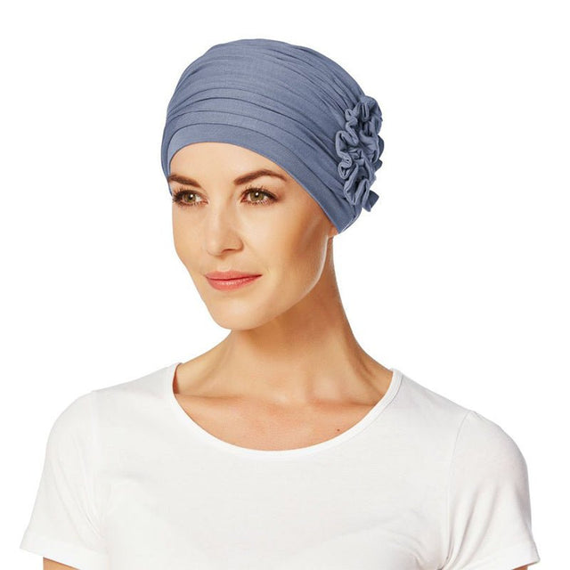Kvinna bär en elegant Lotus turban i lila bambuviskos med veckad design och sidoblomma